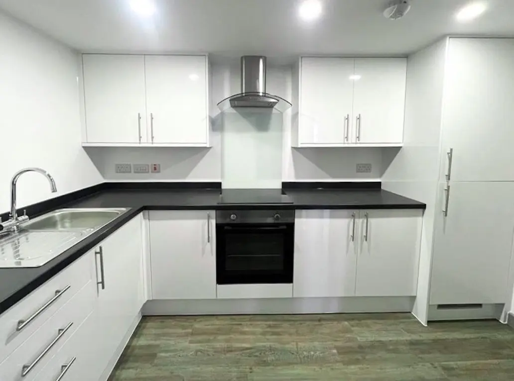 White gloss apartment kitchen with tall fridge freezer housing