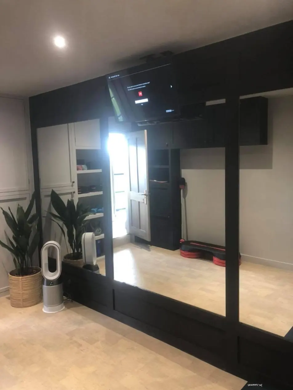Garage converted into a home gym in Lymm, with a mirror wall and fitted units
