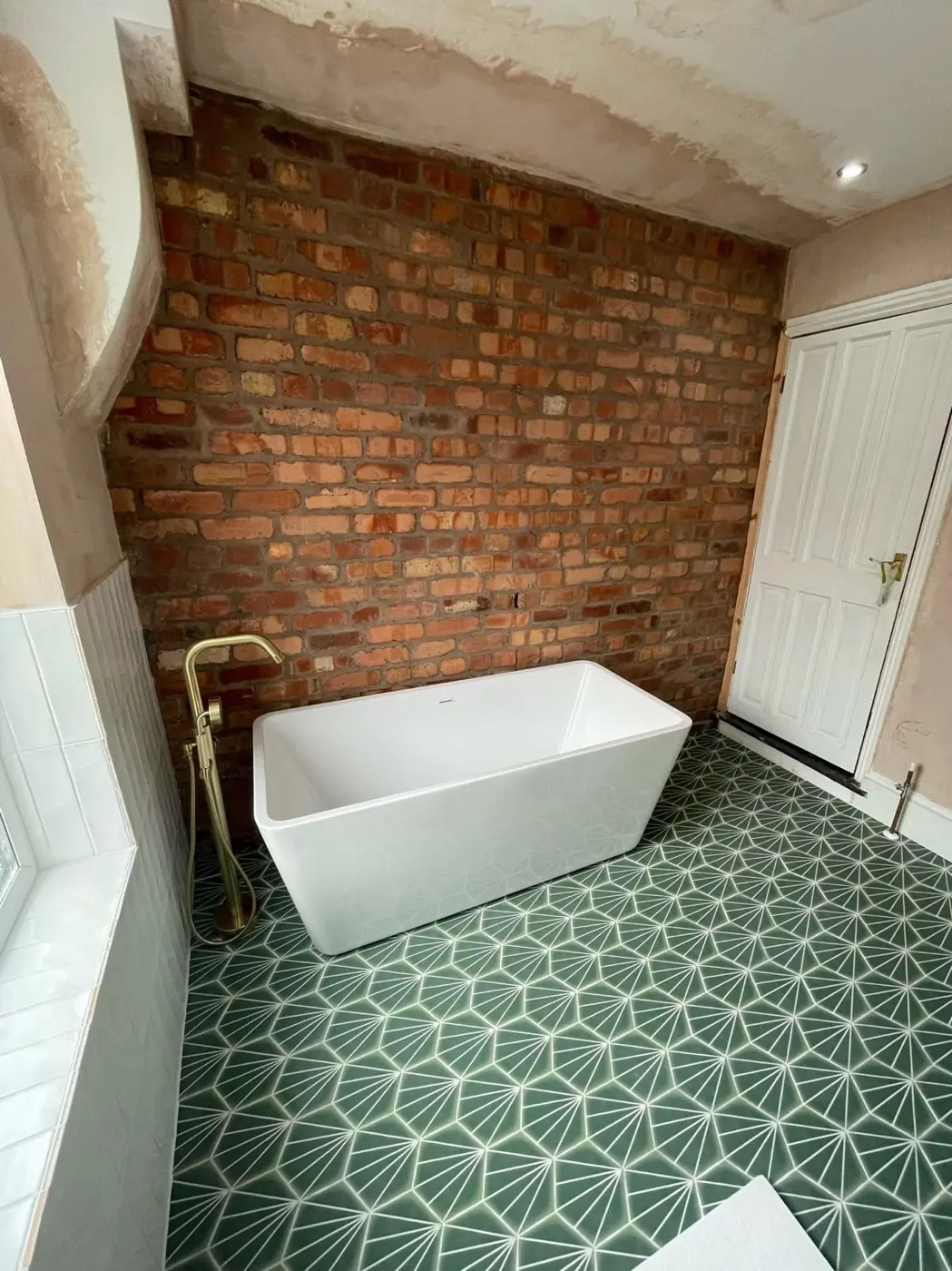 Bathroom mid-build, with the brick wall exposed before tiling