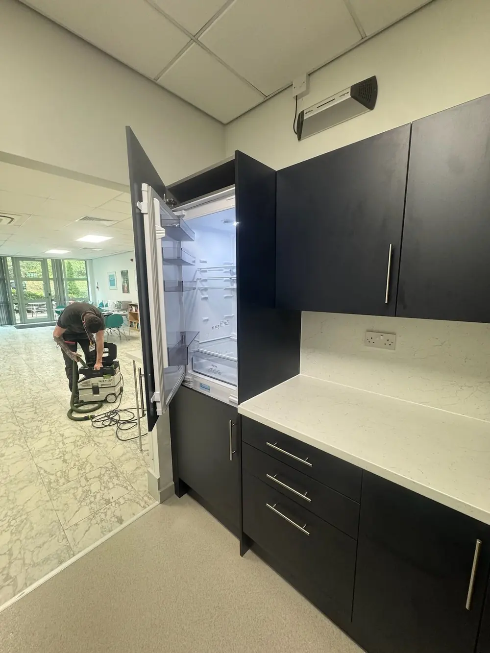 Integrated fridge in a tall housing in an office kitchen