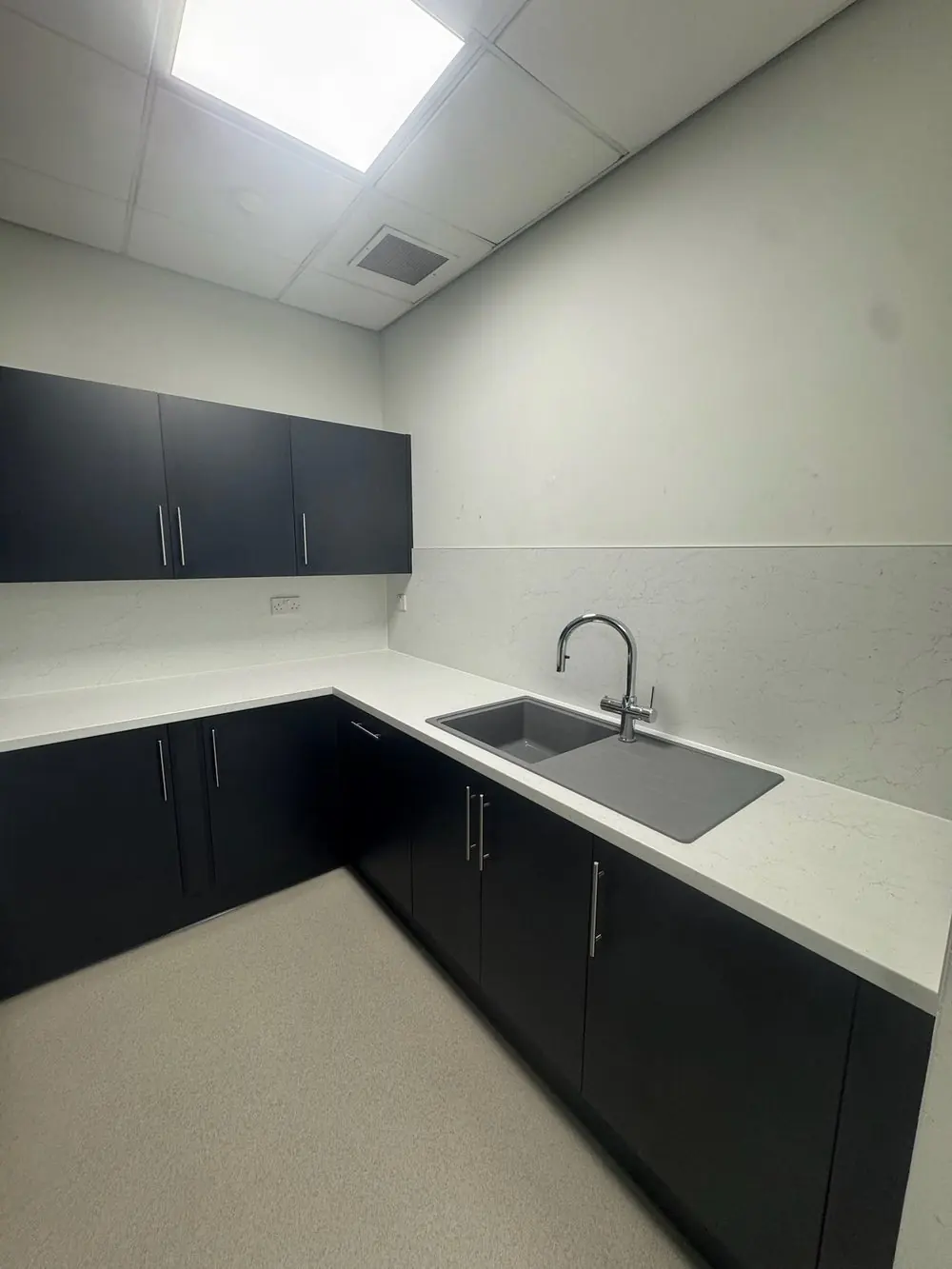 Office staff kitchen with navy units and white quartz-effect worktops